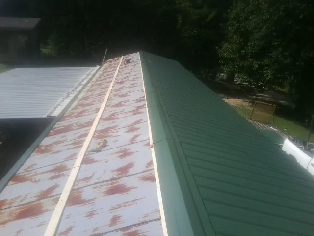 Old rusted panels beside newly installed green metal roofing — Wind Damage Roof Repair by Roofing Brothers in Missoula