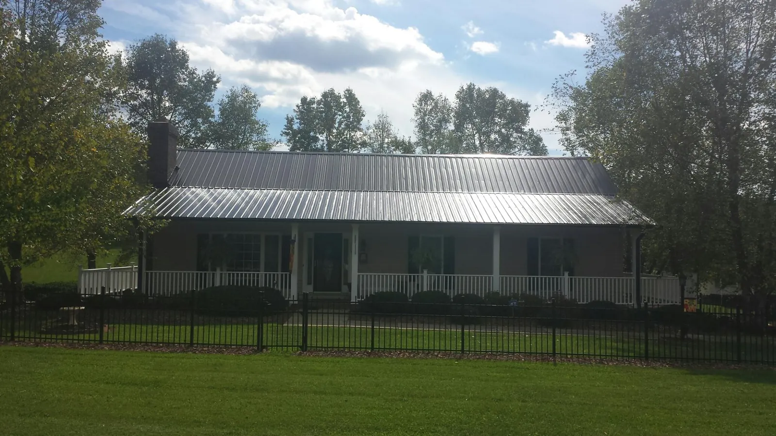 Gray metal roof on a brick ranch with a full width front porch — Gutter Guard Installation work by our crew in Missoula