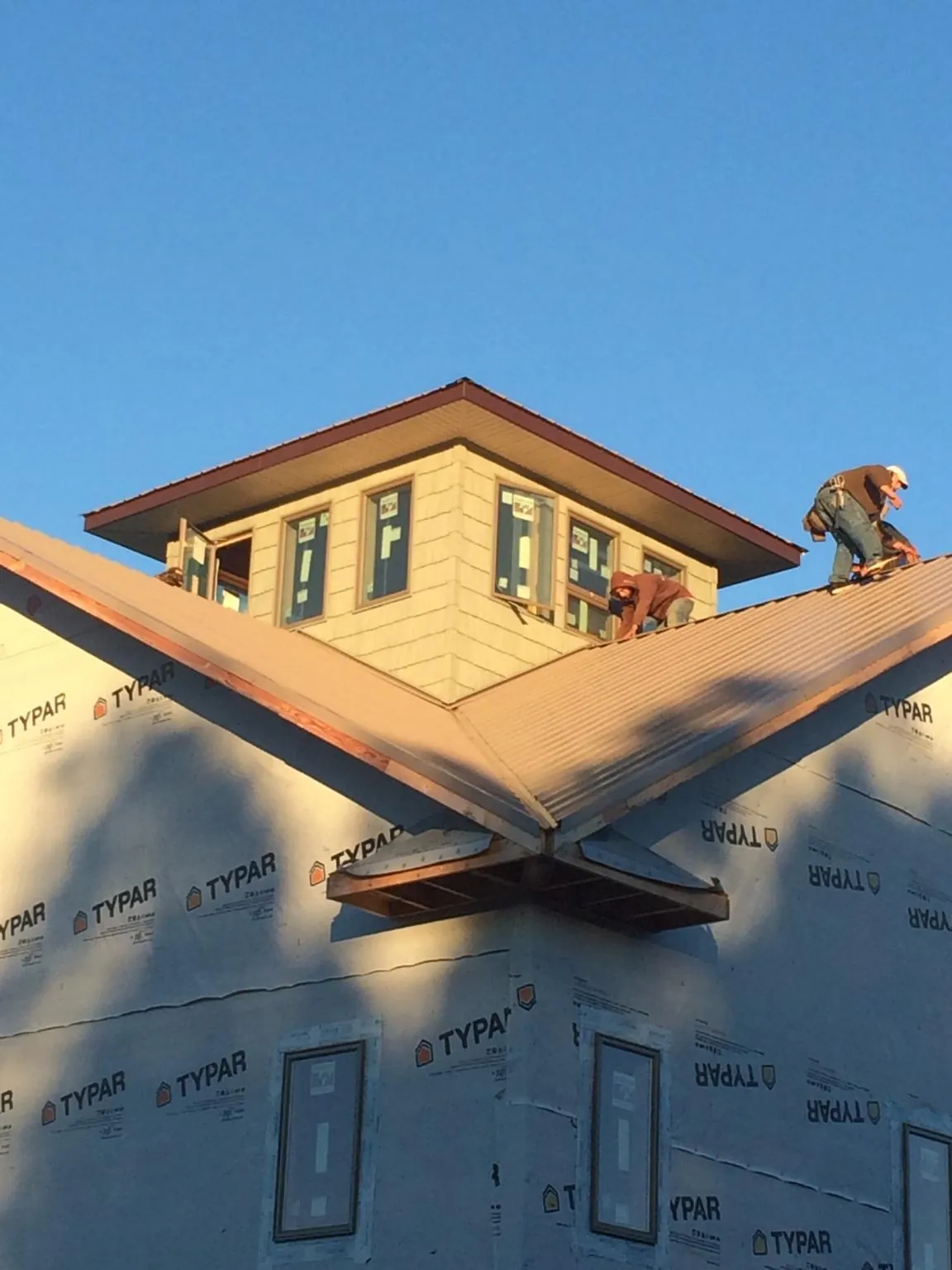 Roofers working around a rooftop cupola on a new metal roof at sunset — Roof Waterproofing in Missoula by Roofing Brothers
